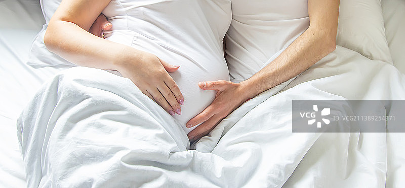孕妇与男人在床上拥抱腹部选择性聚焦图片素材