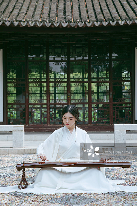 一个汉服美女坐在苏式园林中弹古琴图片素材