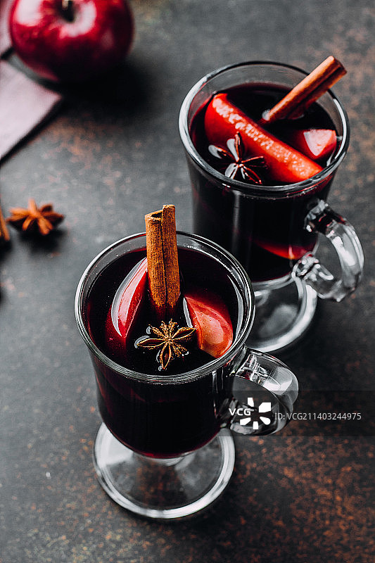 热葡萄酒热饮与柑橘，苹果和香料在玻璃黑暗的混凝土背景图片素材