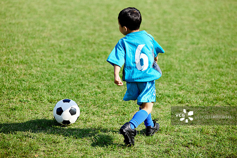 一个日本小孩在城市公园踢足球图片素材