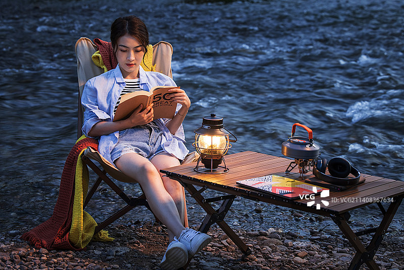 夜晚青年女人在湖边看书图片素材