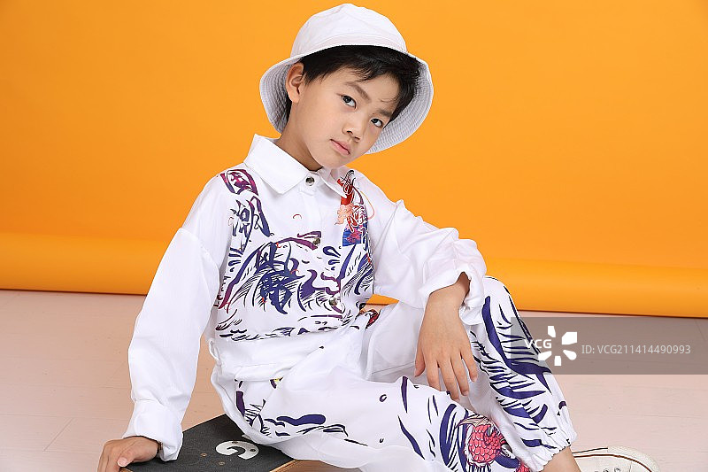 黄色背景下一个坐着的时尚中国小男孩图片素材