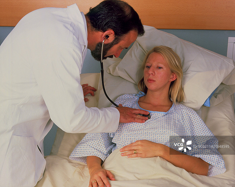 医生用听诊器检查躺在床上的妇女图片素材
