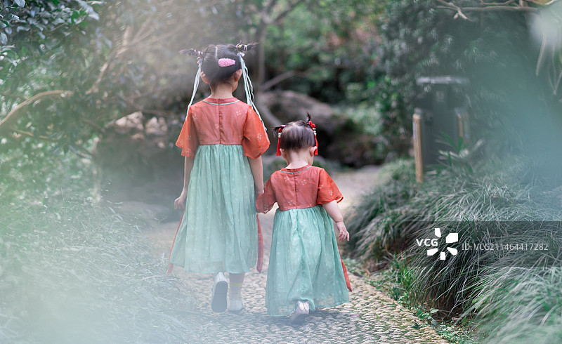 公园里穿着传统服装的姐妹两走过的的背影图片素材