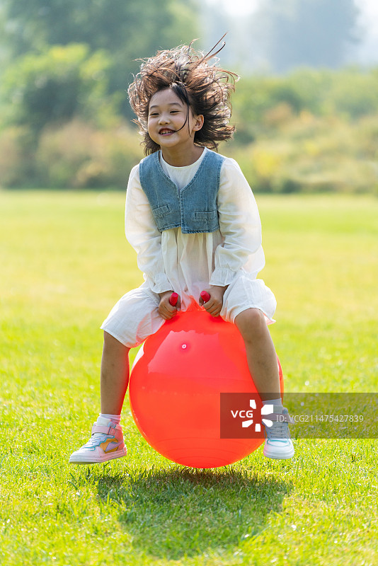 一个小女孩在草地上玩球图片素材