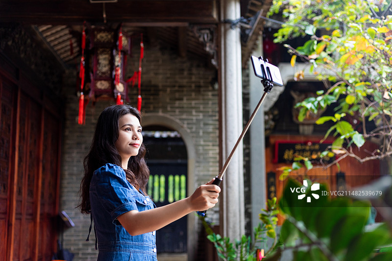 中国女游客在游览古建筑使用自拍杆自拍图片素材