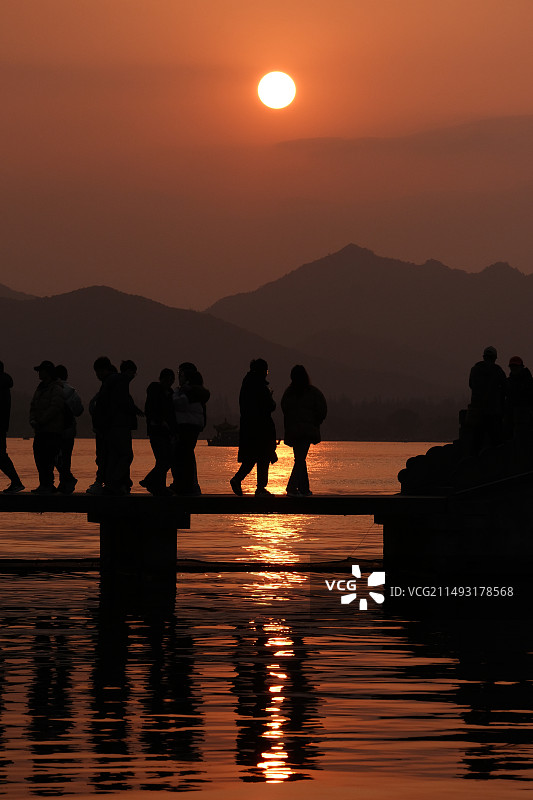 日落时西湖的人们在天空的映衬下剪影图片素材