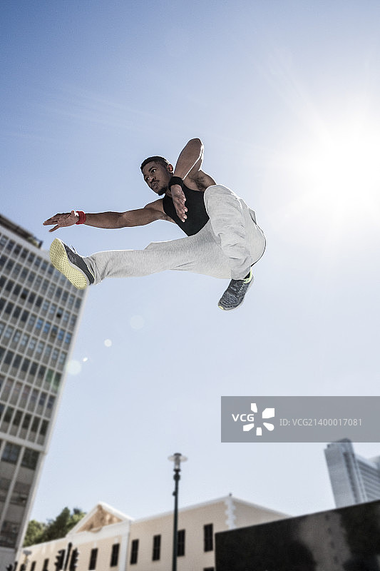 极限运动员在城市建筑前跳跃图片素材