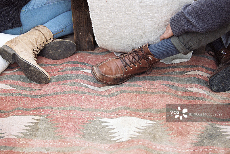 一个苹果果园。两个人坐在毯子上的脚。图片素材
