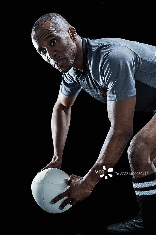 在黑色背景上拿着球时看向别处的橄榄球运动员图片素材