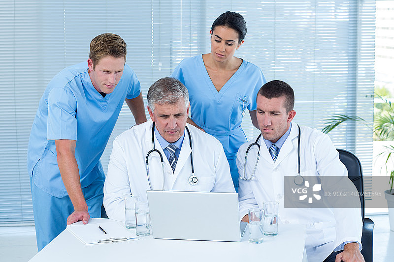在医务室使用笔记本电脑工作的医生团队图片素材