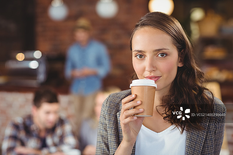 微笑的年轻女子在咖啡店喝外卖杯的肖像图片素材