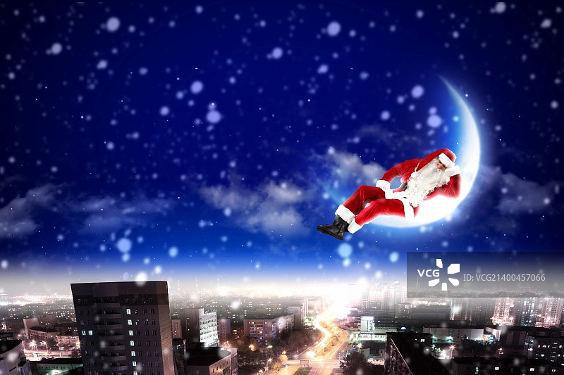 夜晚城市上空月亮上的圣诞老人图片素材