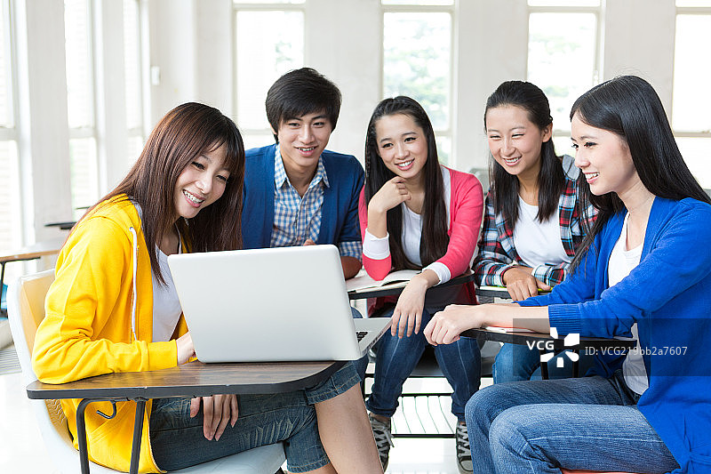 男女大学生在教室看笔记本电脑图片素材