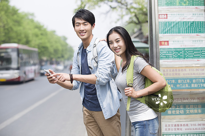 年轻情侣在公交站等车图片素材
