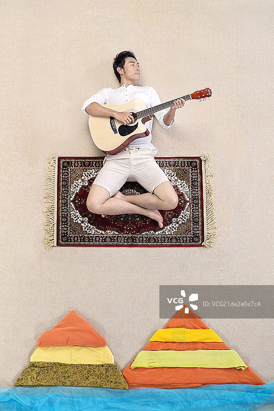 坐在魔毯上弹吉他的男士图片素材