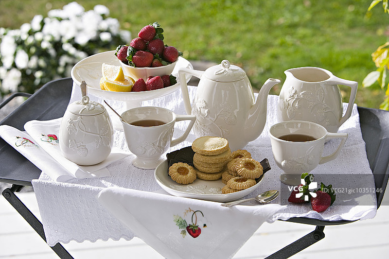 传统的下午茶放在茶盘上，茶盘上放着白瓷和草莓。图片素材