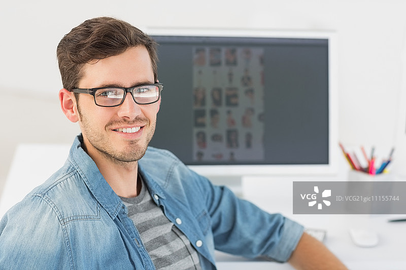 一个随意的男性照片编辑在电脑前的肖像在办公室图片素材