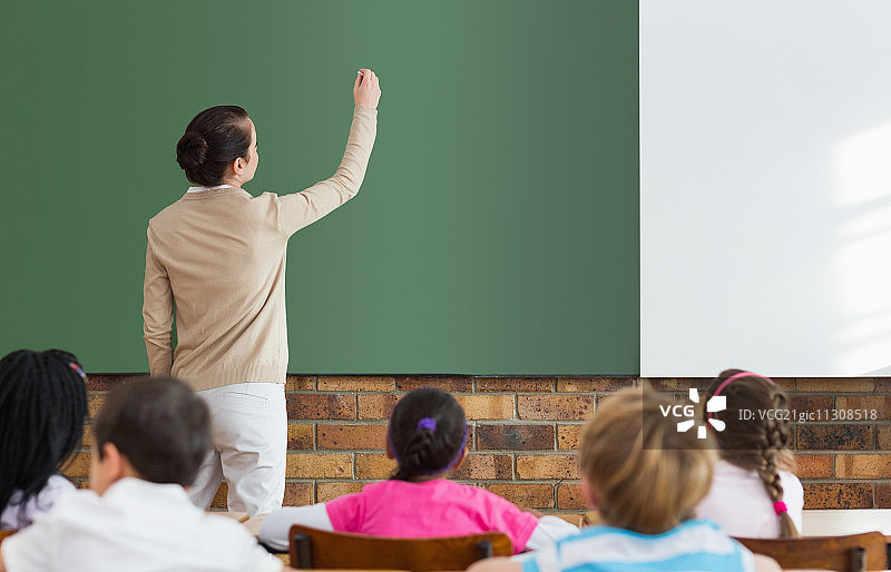 小学生在小学黑板前听老师讲课图片素材