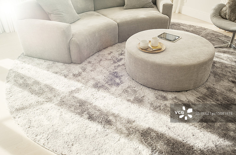 客厅弧形沙发和搁脚凳下的圆形地毯图片素材