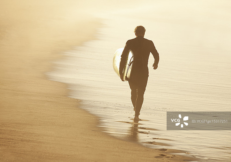 年老的冲浪者带着冲浪板在海滩上图片素材