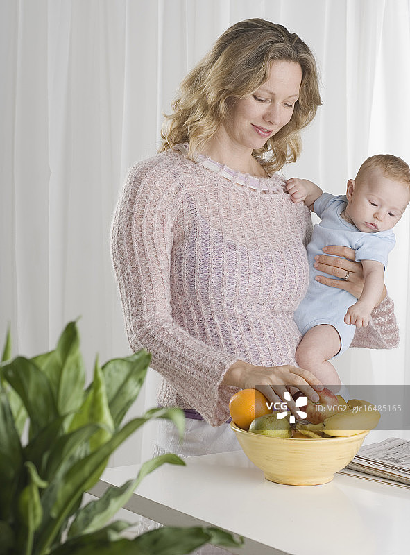 年轻的母亲带着男婴和水果盘图片素材