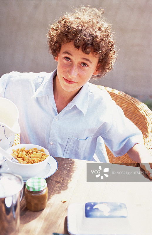 男孩在阳光露台上吃早餐图片素材