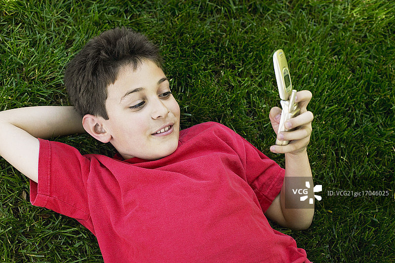 男孩躺在草地上看手机图片素材