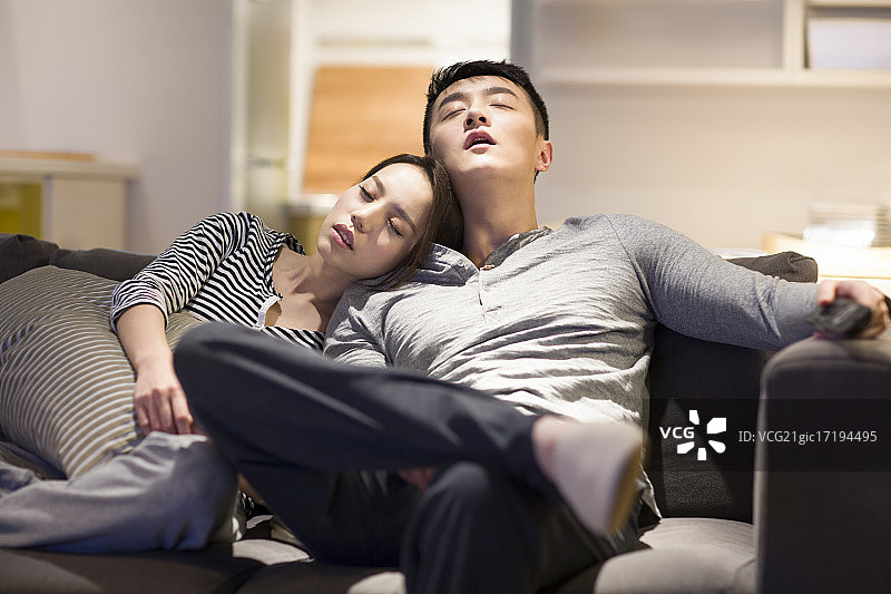 疲倦的年轻情侣在客厅沙发上睡觉图片素材