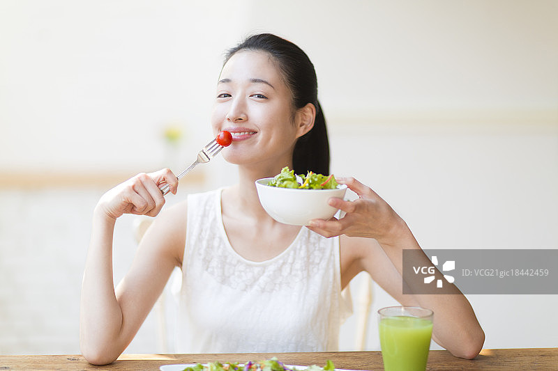 微笑的女人在吃沙拉图片素材