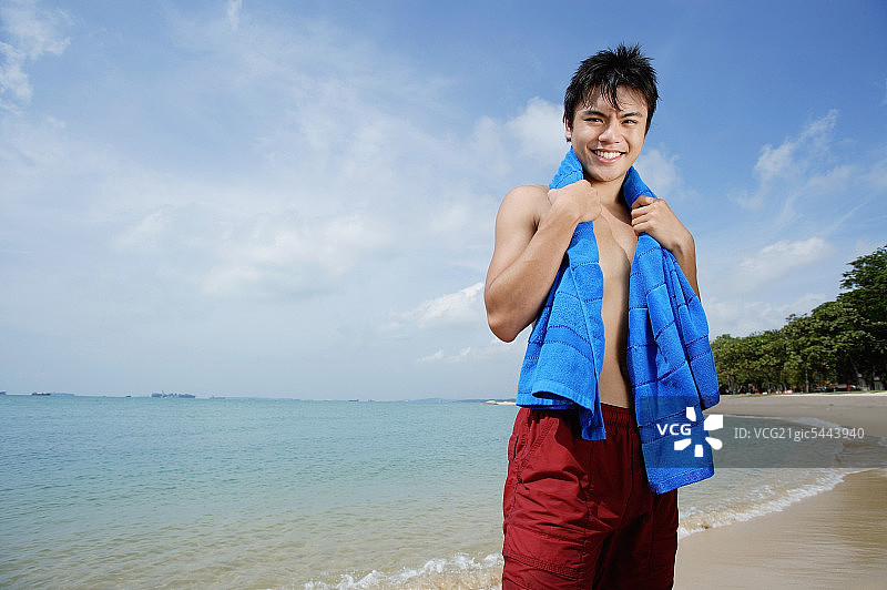 一个男人站在沙滩上，脖子上挂着毛巾图片素材