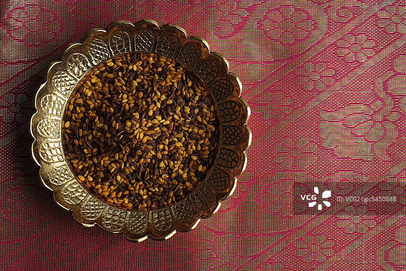 印度消化mukhwa种子在黄铜盘子上的粉红色纱丽布图片素材