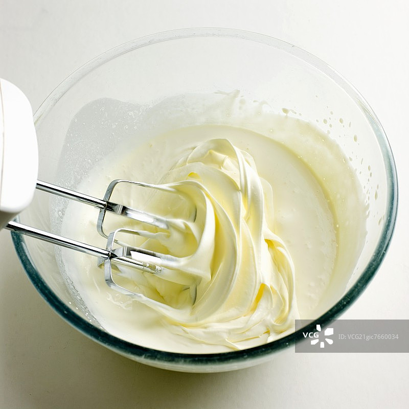 奶油在一个玻璃碗里，用电动搅拌器搅拌图片素材