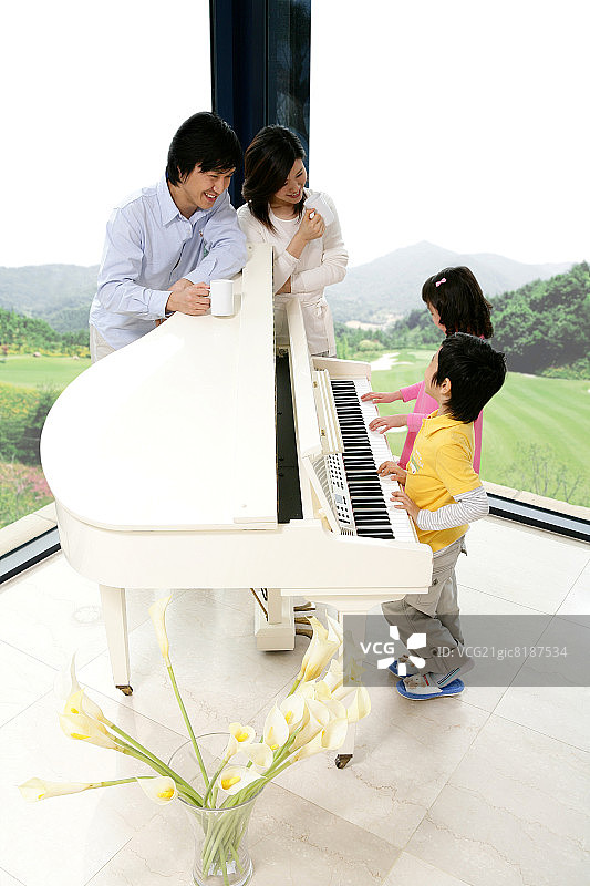 父母带着孩子(6-11岁)弹钢琴，居高临下图片素材