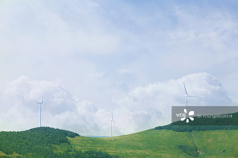 风力涡轮机上郁郁葱葱，绿意盎然，景观中布满云雾。图片素材