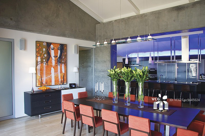 在一个设计师厨房前的现代用餐区周围布置了混凝土，厨房用蓝色的灯光和一个长柜台照明图片素材