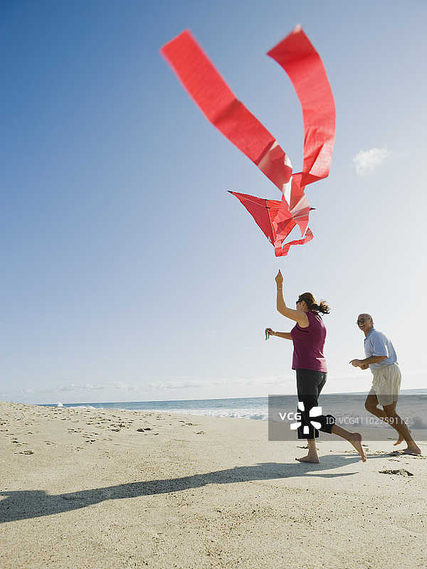 一对夫妇在海滩上放风筝图片素材