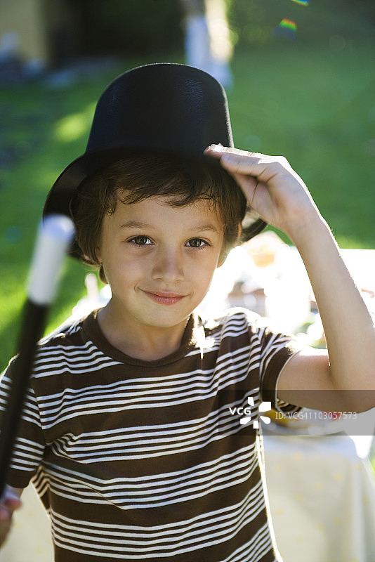 男孩拿着魔杖和魔术师的帽子，肖像图片素材