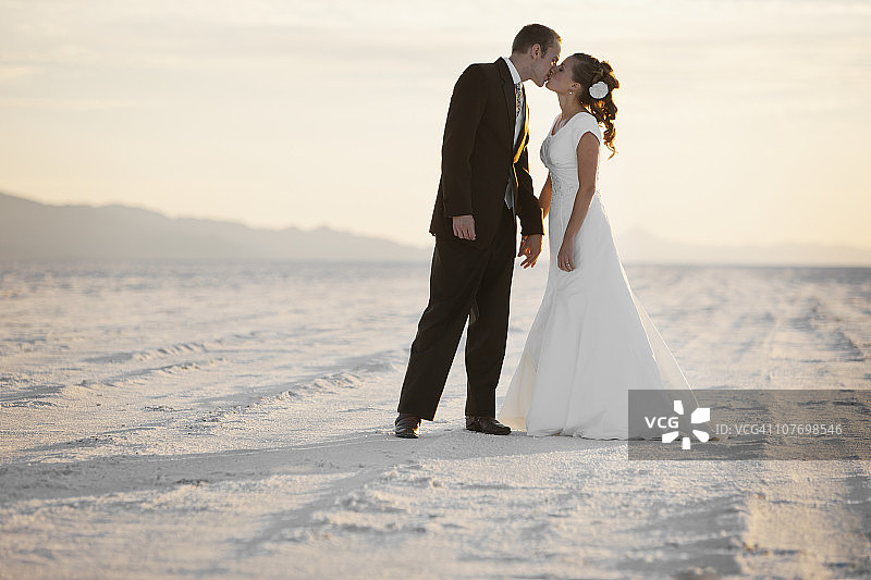 美国，犹他州，波恩维尔盐滩，新郎亲吻新娘在沙漠图片素材