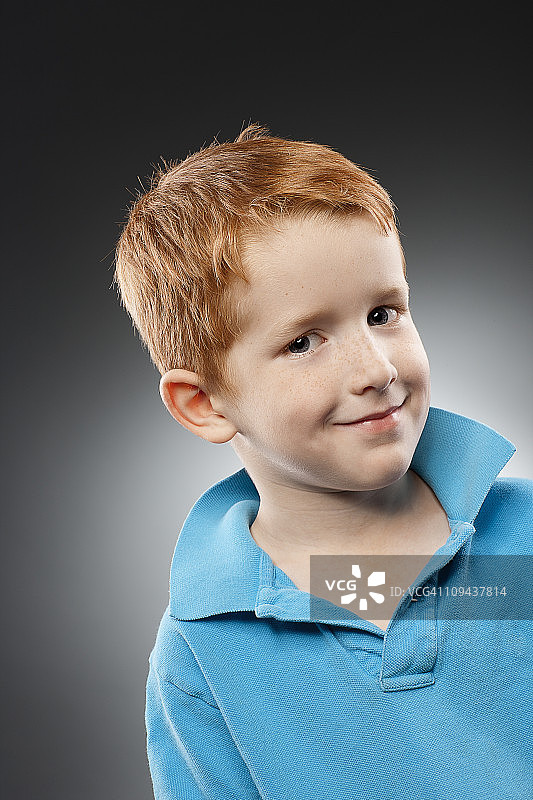 身穿蓝色马球衫的红发男孩(4-5岁)的照片，在摄影棚拍摄图片素材