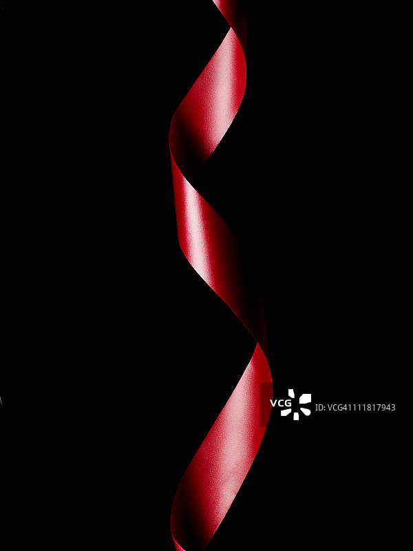 红色丝带在黑色背景上扭曲。图片素材