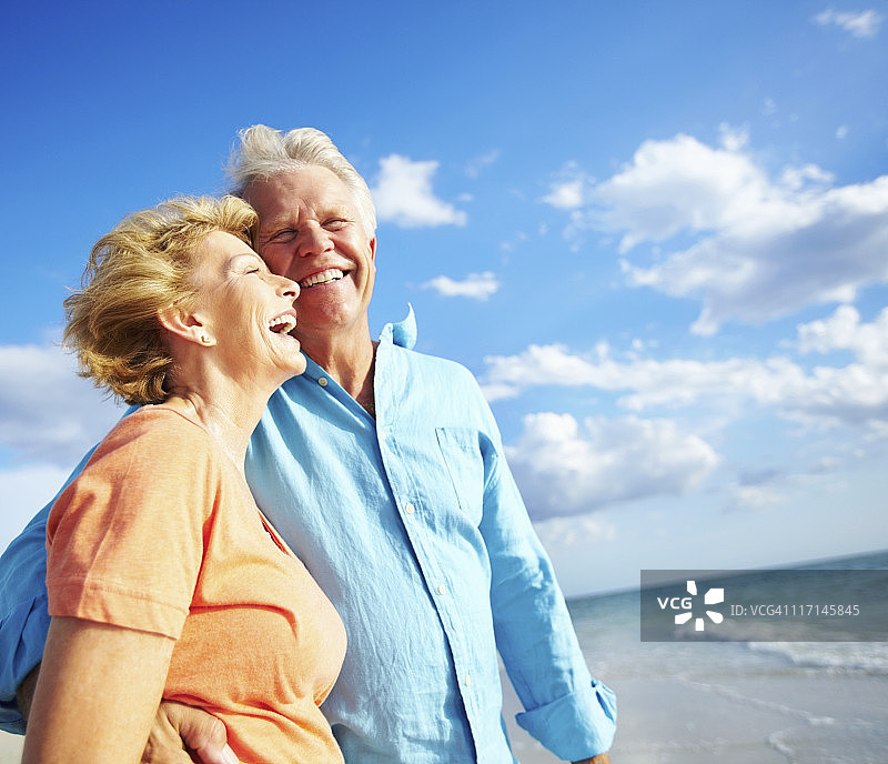 快乐的退休夫妇在海滩上拥抱图片素材