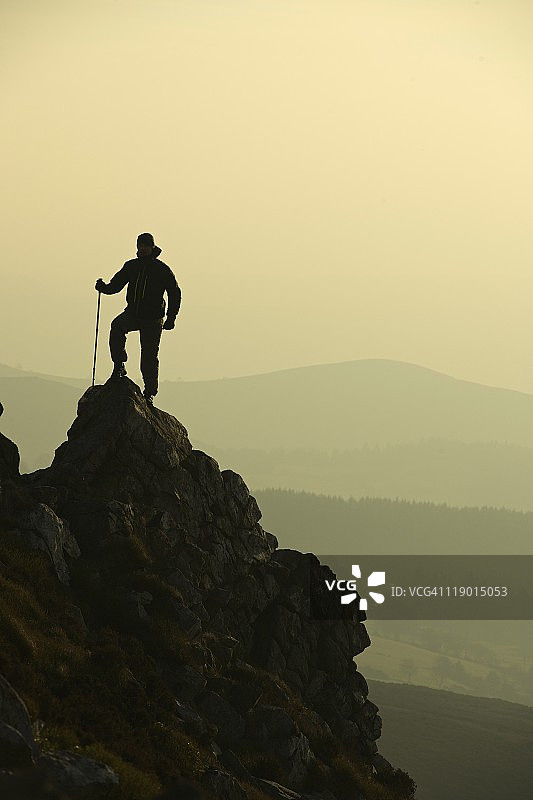 男子在岩石山坡上徒步旅行图片素材