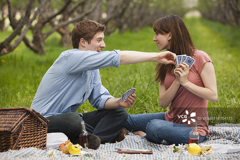 美国，犹他州，普罗沃，一对年轻夫妇在果园野餐时打牌图片素材