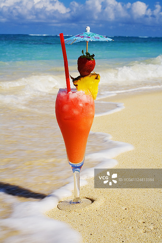 海滩上的热带鸡尾酒，海浪冲刷着沙滩。图片素材