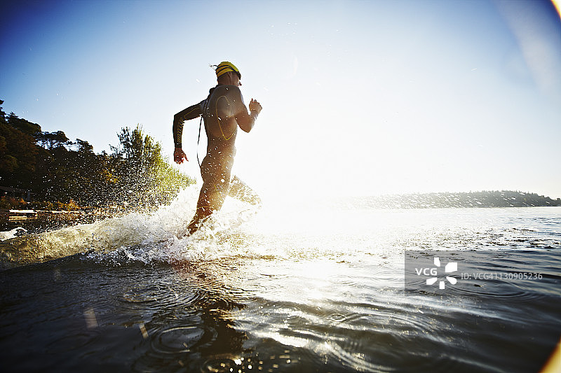 男性铁人三项运动员在日出时跳入水中图片素材