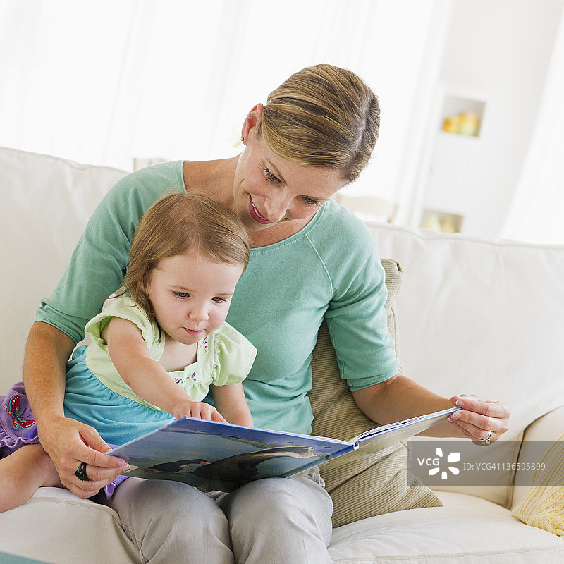 母亲和女儿(2-3)在沙发上看书图片素材