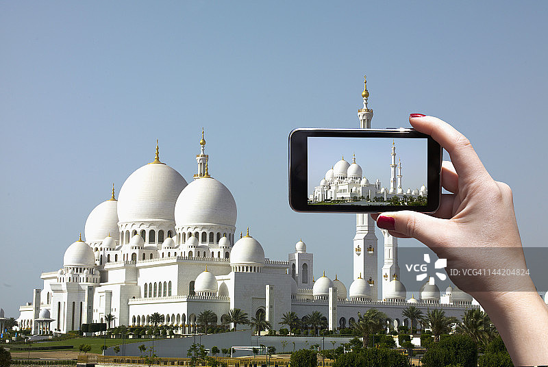 阿拉伯妇女用iPhone拍摄清真寺图片素材