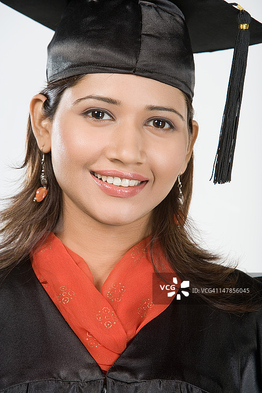 年轻女子戴着学位帽，微笑着，画像图片素材