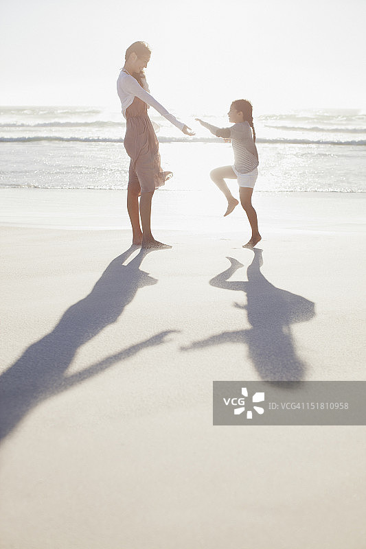 母亲和女儿在阳光明媚的海滩上图片素材